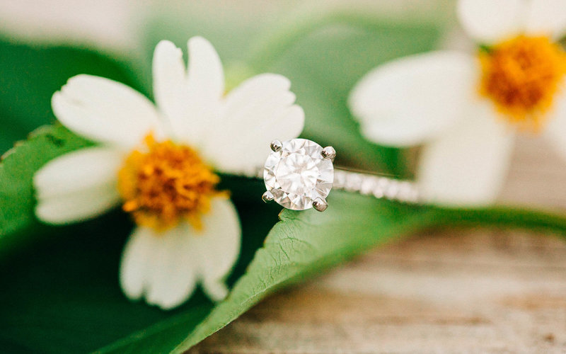 Engagement ring beside small white flowers