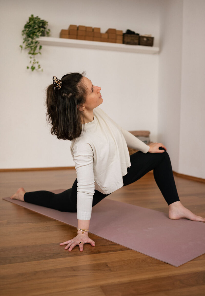 eine Yogalehrerin hält eine Stretchposition in ihrem Yogastudio
