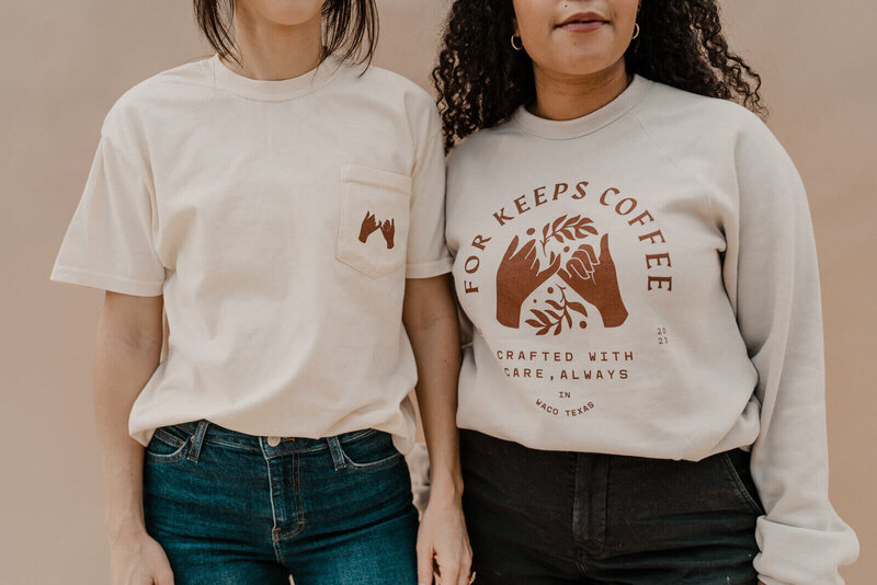 Two women in matching t-shirts with the phrase "Keep it to coffee" displayed prominently, smiling together.