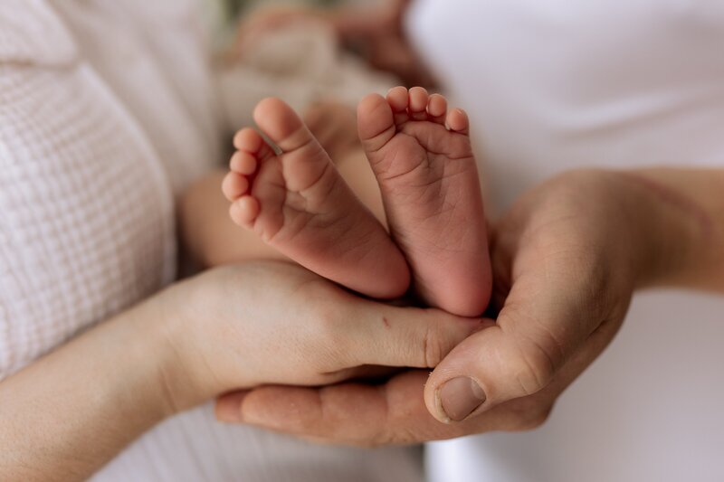Zwei Haende die zwei Babyfuesse halten