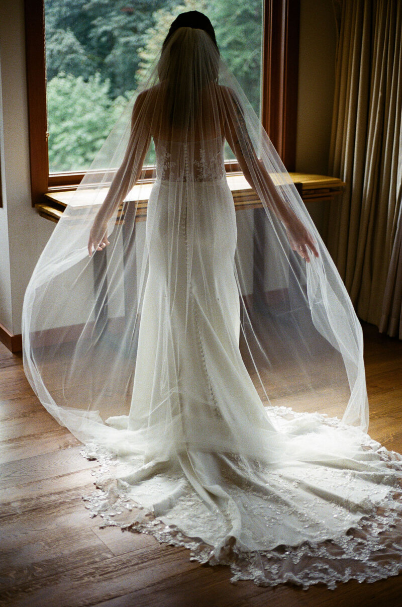 Bride stands in a window showcasing her gown