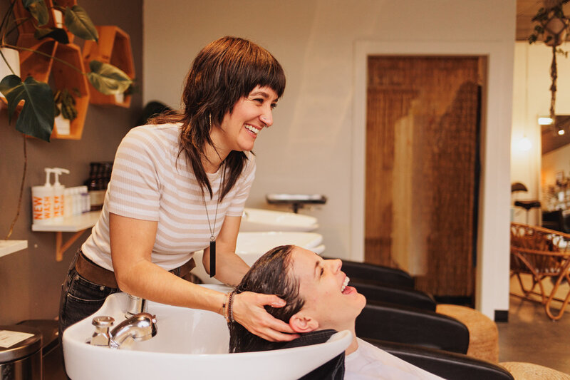 Eugene hair salon owner Chelsea smiles as she washes a client's hair.