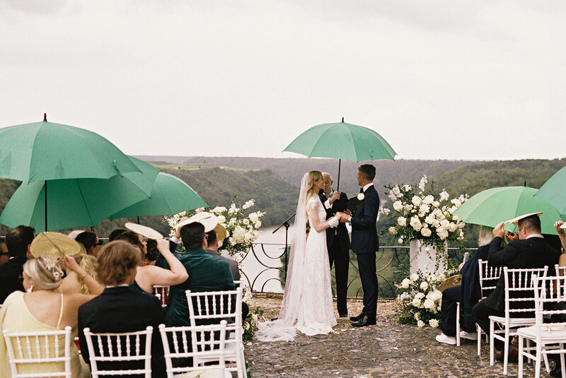 Bride and groom exchanging vows under umbrellas during a romantic rainy ceremony at Altos de Chavón — emotional and cinematic moment captured by Asia Pimentel Photography.