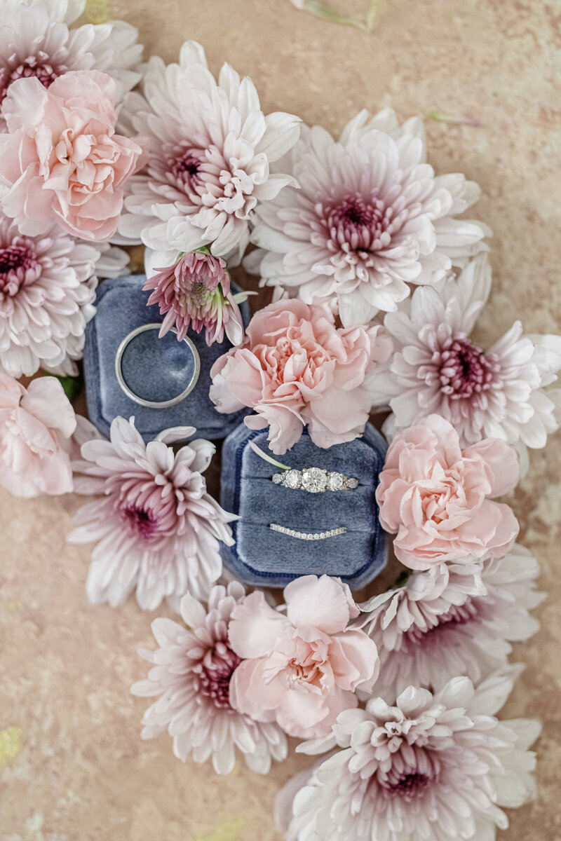 wedding rings photographed up close surrounded by pink flowers.