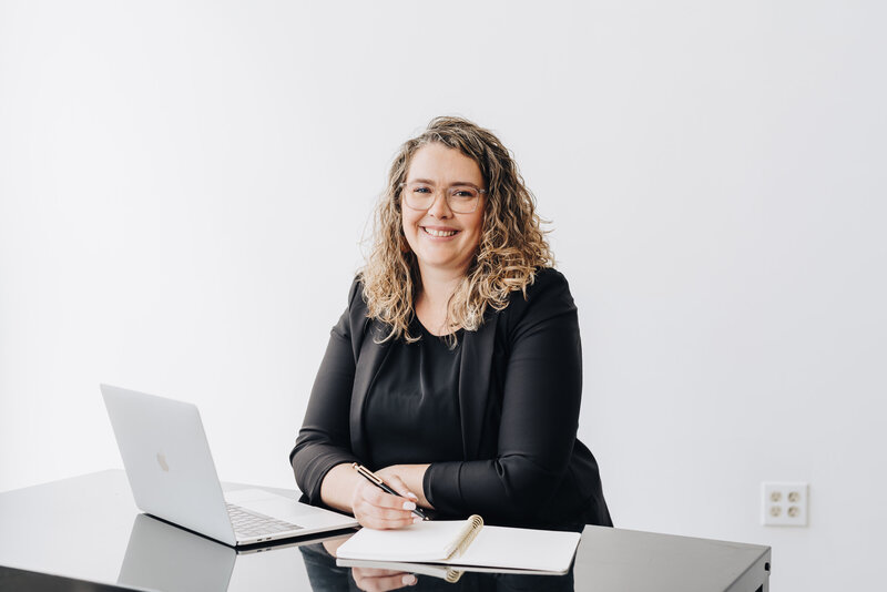 Owner of Woodall Creative Co sits at her desk with her computer smiling at the camera