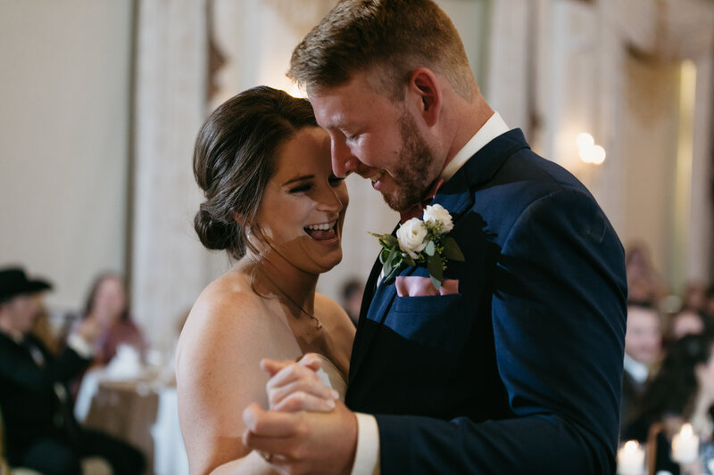 A bride and groom laugh during their first dance