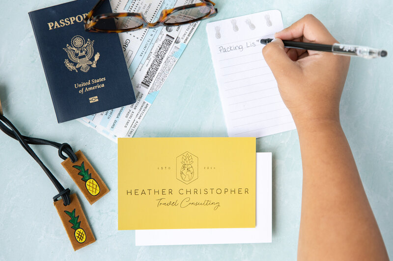 travel advisor brand shoot areal view of plane ticket, passport and other travel items while hand is writing a packing list