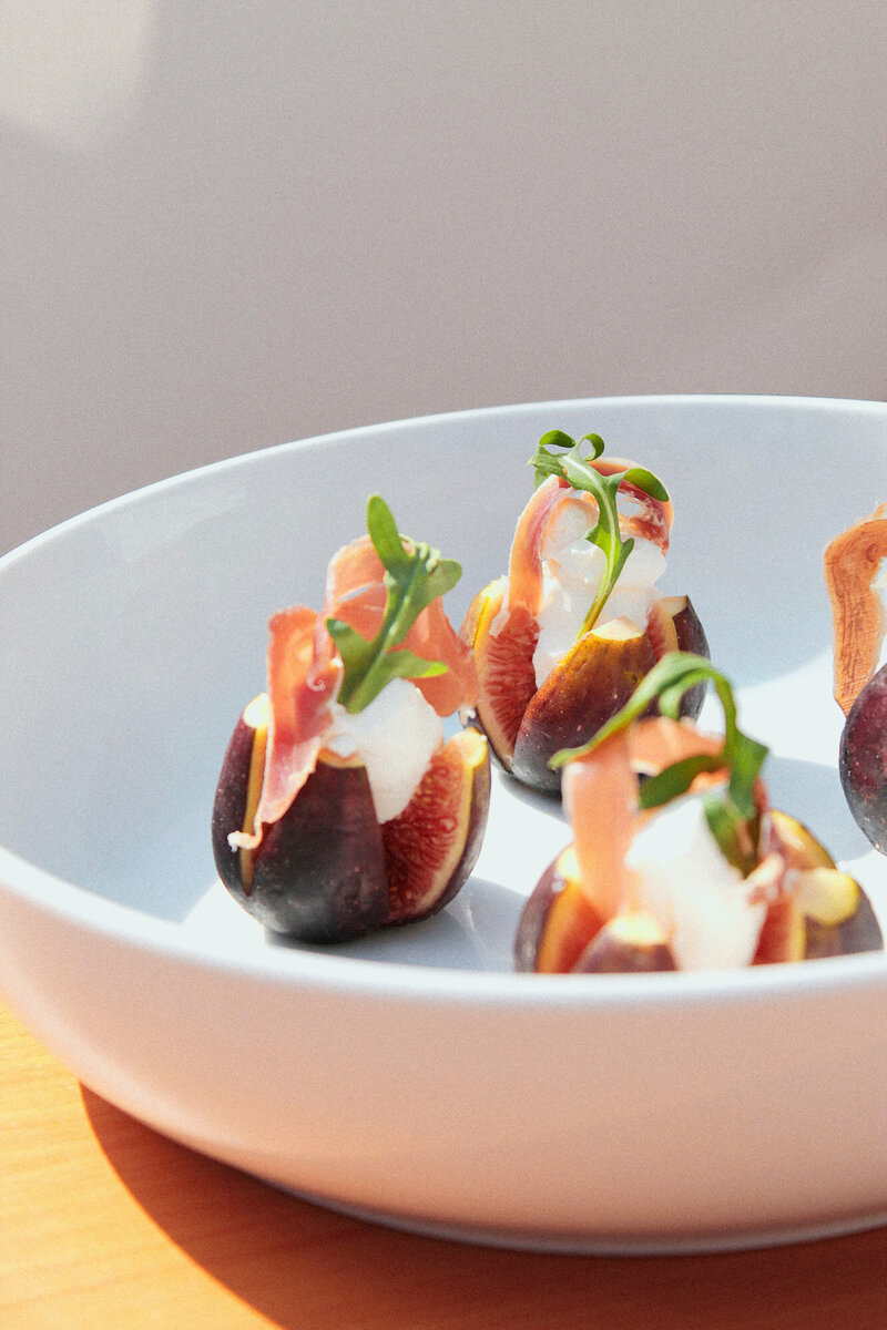 close-up of a white bowl containing a few fig halves