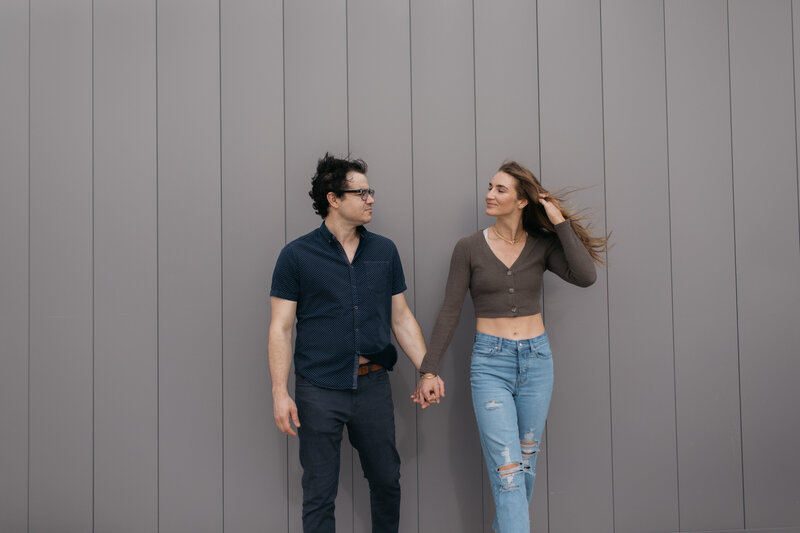 Downtown couple holding hands with wind blowing hair