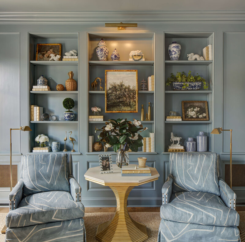 A blue bookshelf with two stylish blue chairs