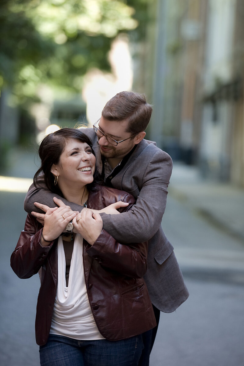 A person standing behind their partner and hugging them 