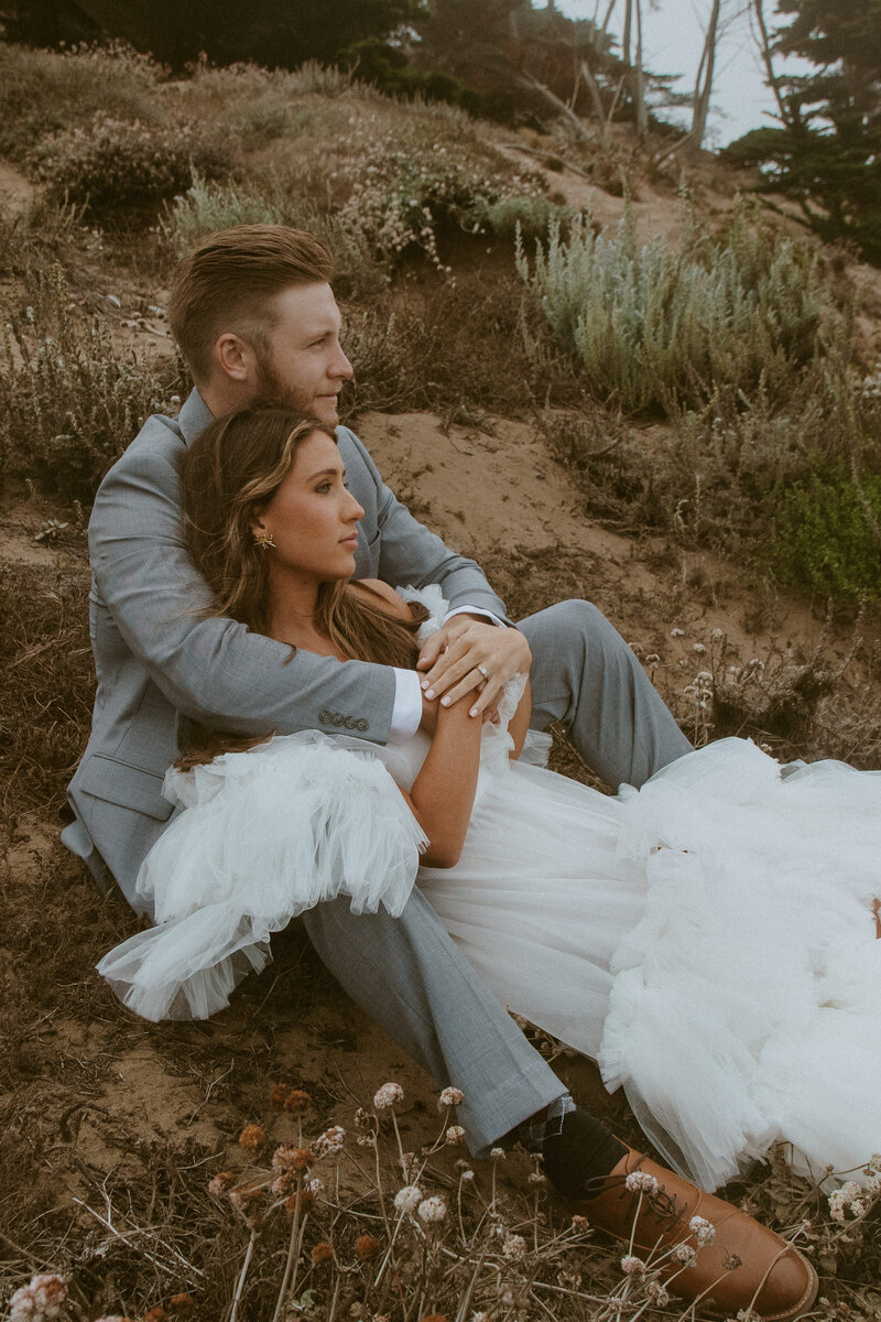 Bride and groom embracing on coastal sand