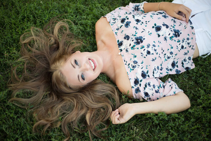 Girl laying down in grass with floral shirt
