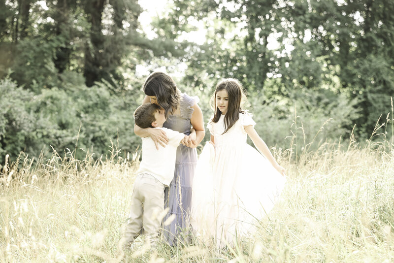 Outdoor Asheville Family Session - Mom kissing little boy's head with her daughter in white dress