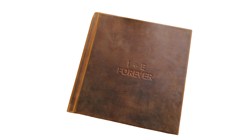 a brown leather wedding album with a custom stamp engraved on the cover