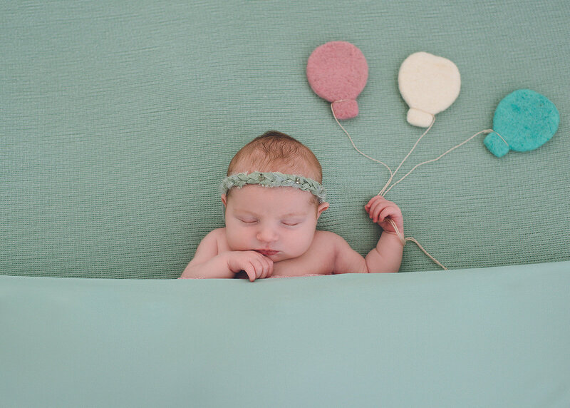 newborn baby girl posed with felted balloons