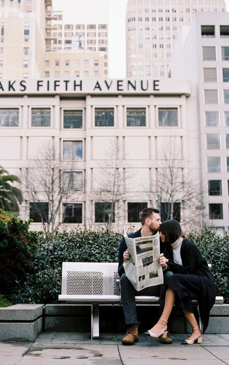 couple sits on a bench with newspaper in downtown san francisco