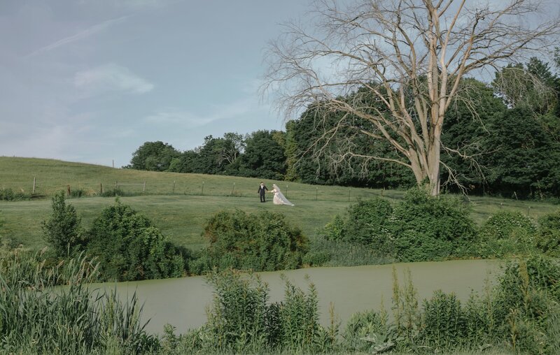 Bride and Groom walk through a field during their wedding reception.