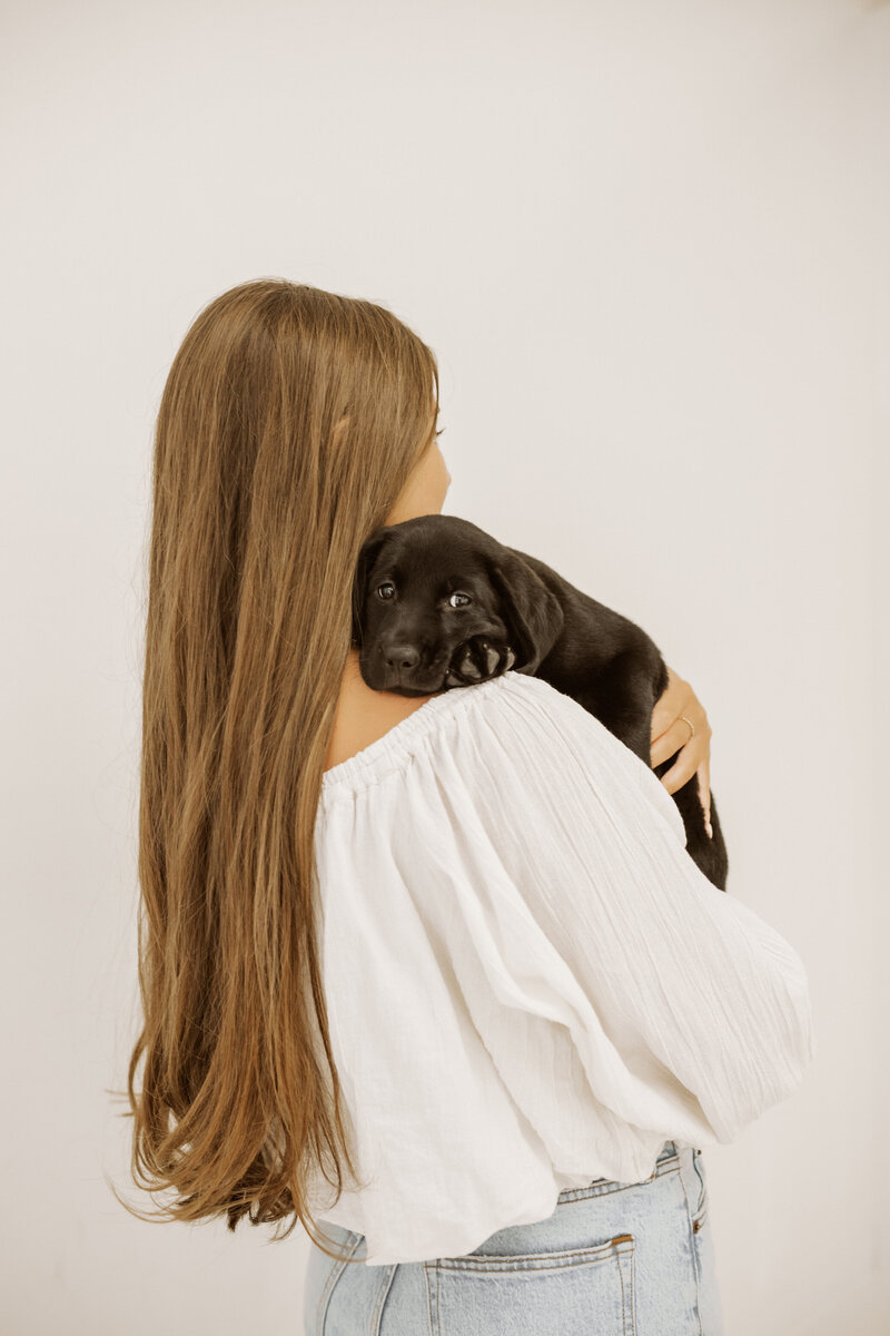 Girl holding black labrador retriever puppy