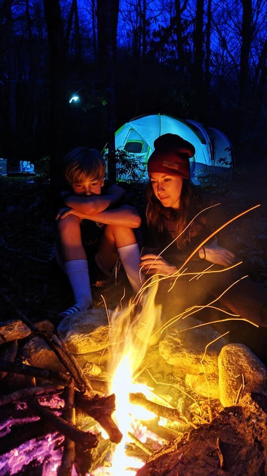 mother and son sit around campfire