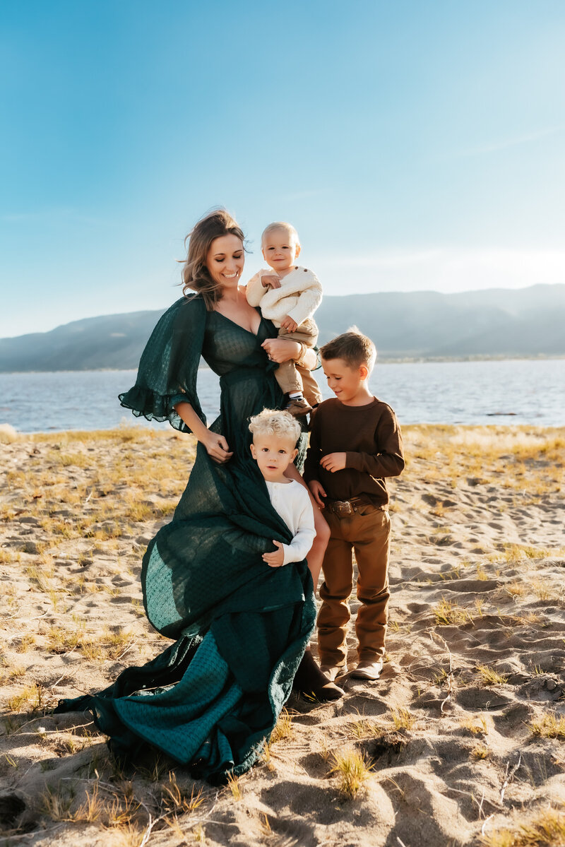 A mother in a flowy emerald dress with her four boys at Washoe Lake.