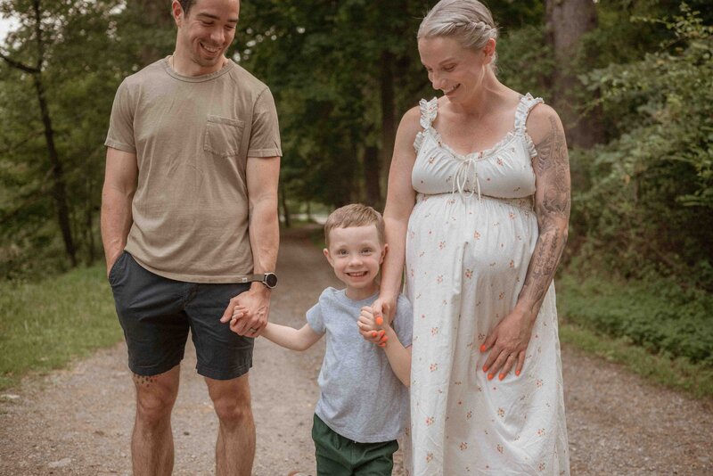 Pitssburgh family in North Park smiling down at their son during an outdoor maternity session.