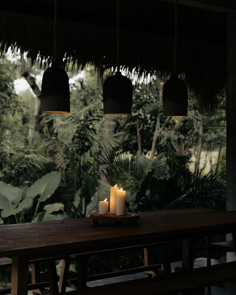 Timber dining table with candles and pendant lighting at Ronja Boutique Hotel, Bali.
