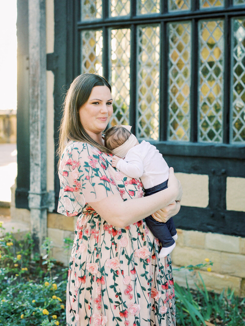 A mother holding a baby and looking off into the distance at a Richmond family photography session by Katie Stansfield Photography.