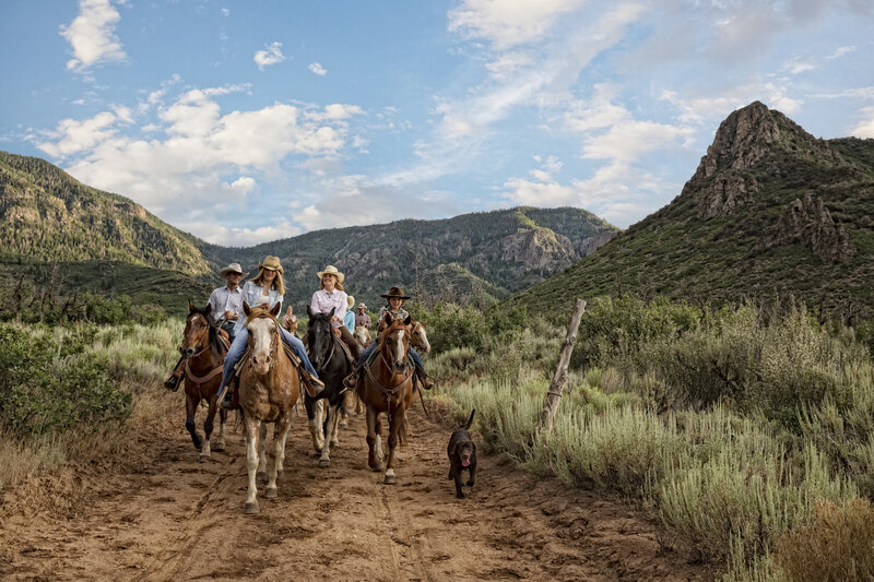 family riding horses in mountains smiling