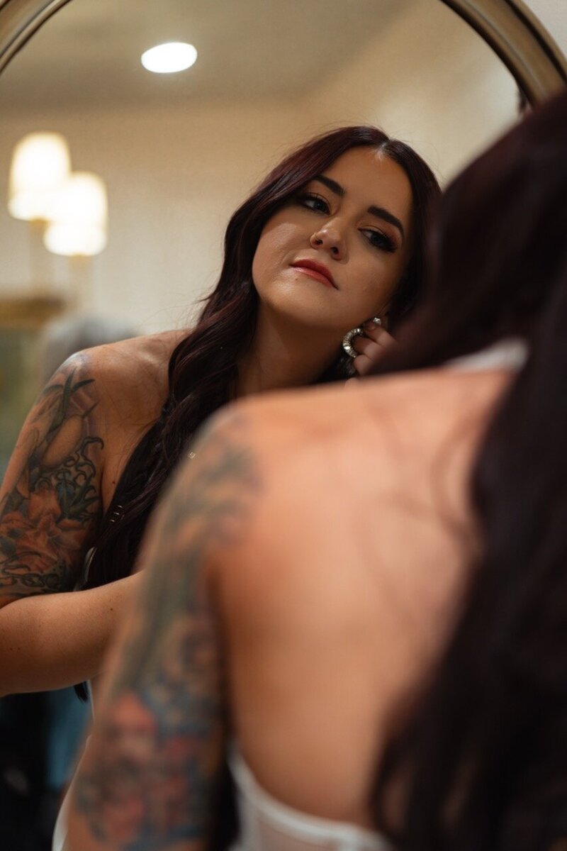 Woman putting on earrings in mirror