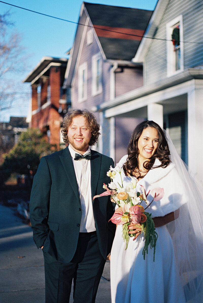 Bride and groom stand casually, being greeted by friends and family