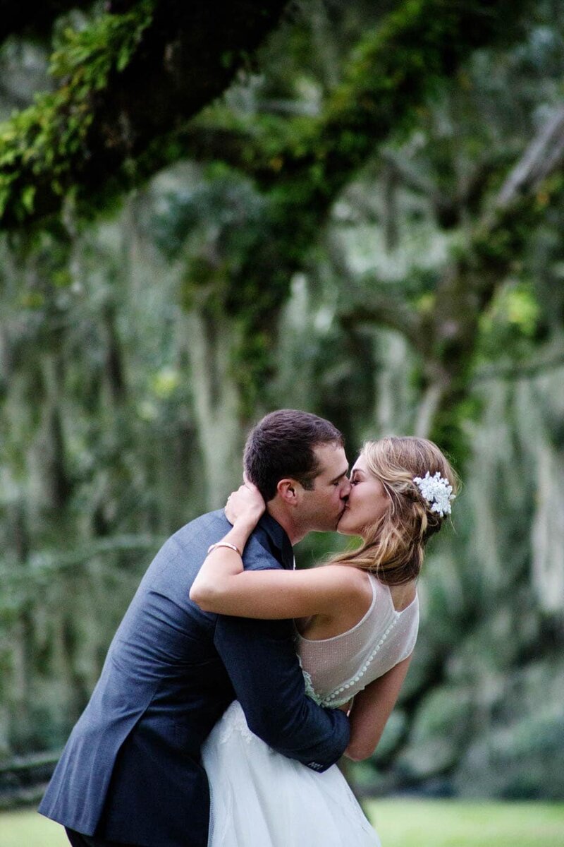 a bride and groom kiss in front of mossy oak trees
