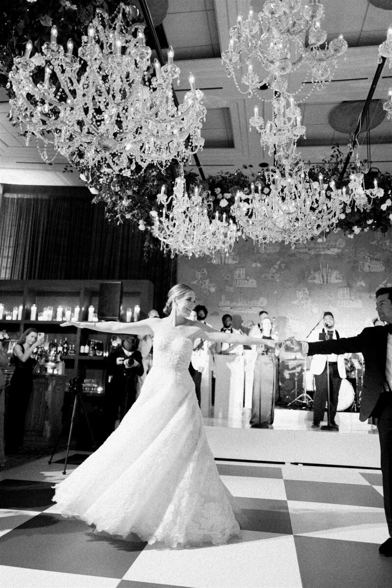 Newlyweds dancing under a canopy of twinkling lights and white floral decor at their reception.