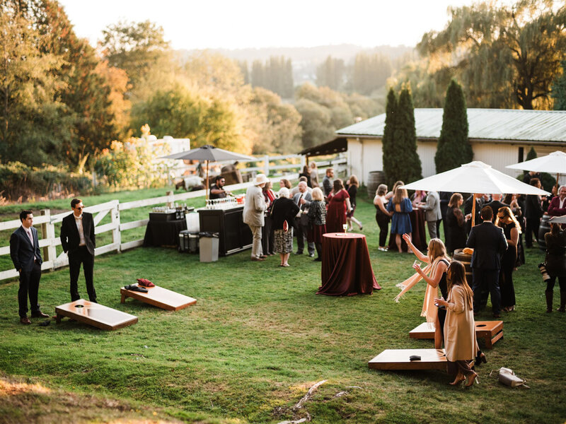 Guests enjoy an outdoor cocktail hour, complete with lawn games and a bar station, set against the backdrop of golden-hour lighting