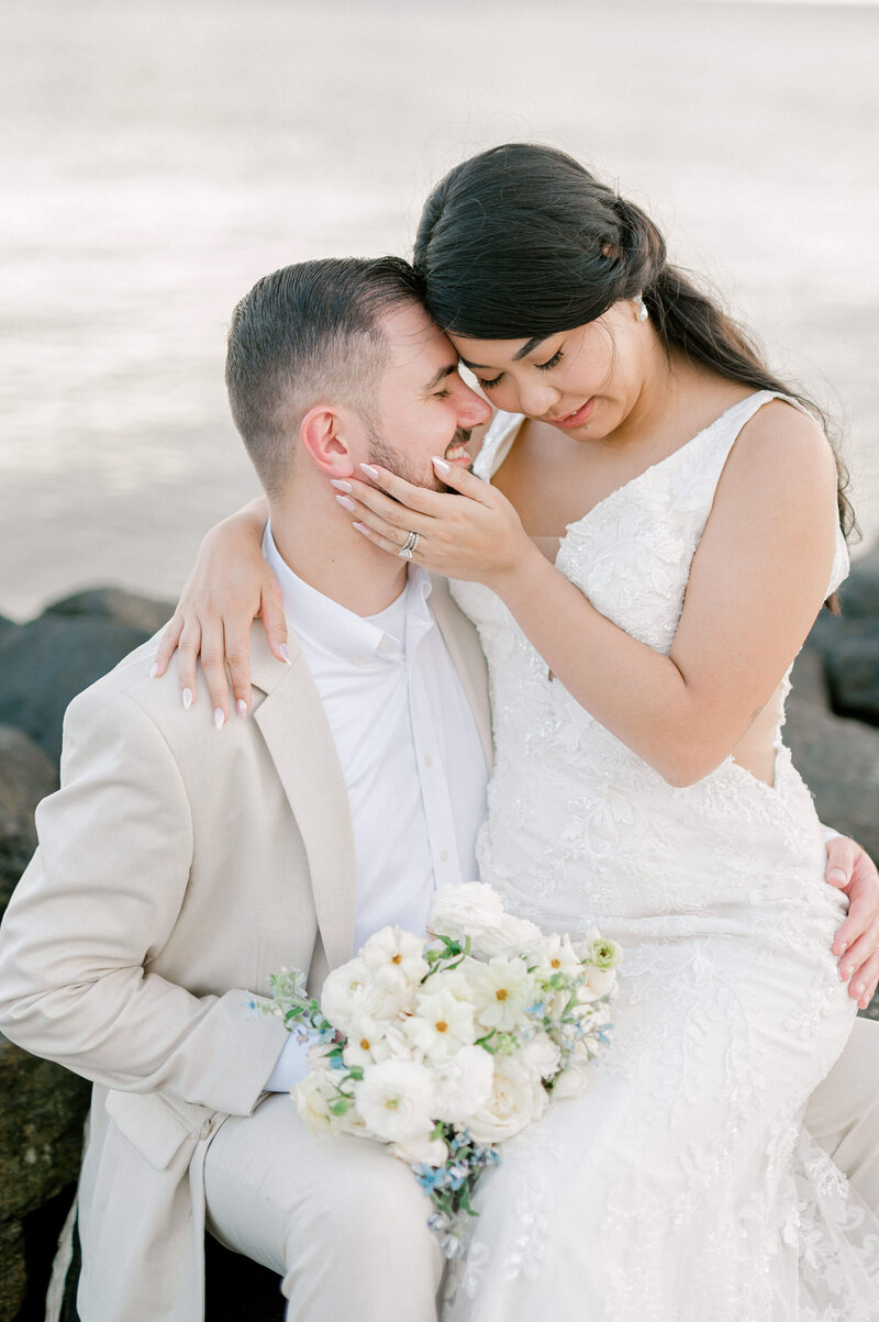 a bride sitting in her groom's lap and holding his face