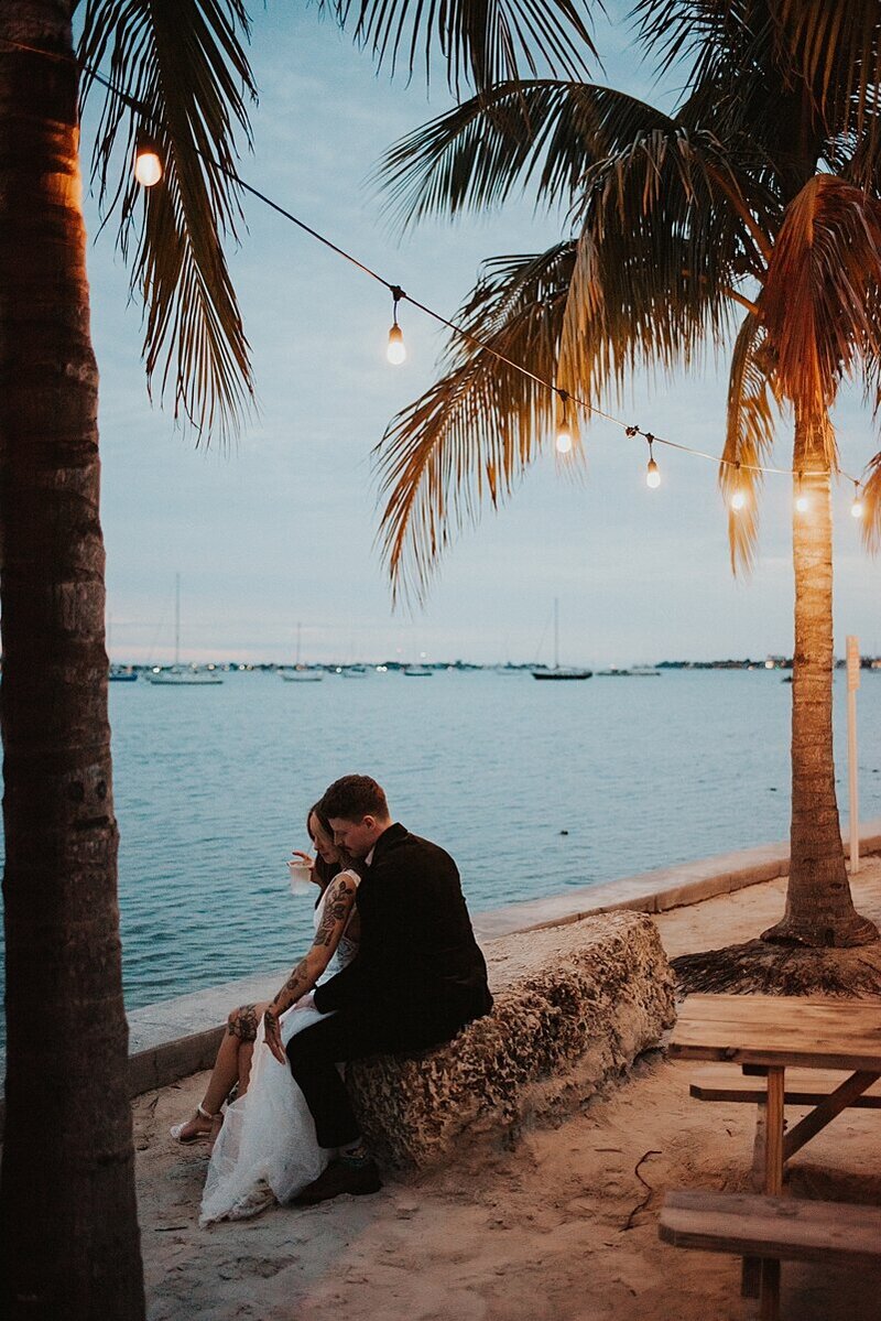 Bride and groom sipping cocktails at the end of a tiki bar watching the sunset after their Sarasota elopement