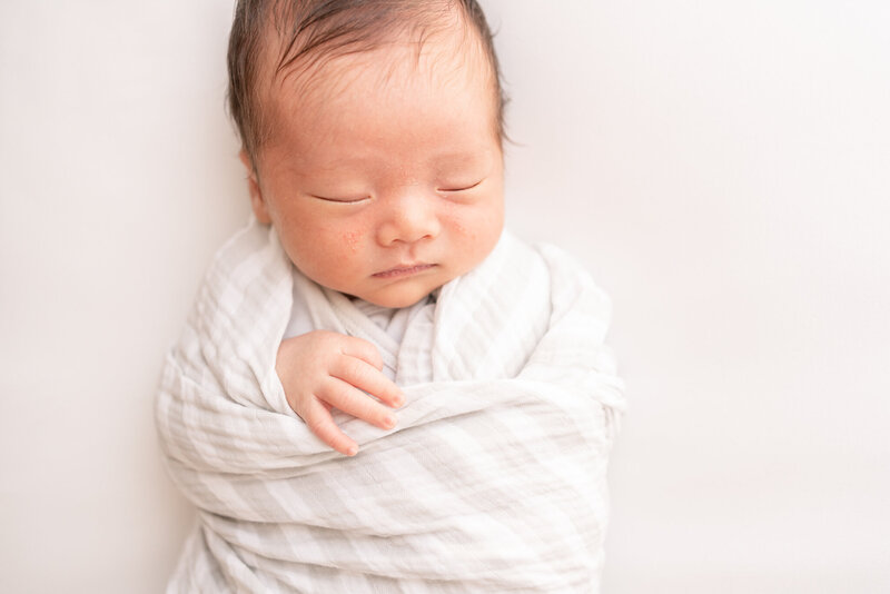 Sleeping newborn boy on his side with his hands under his cheek