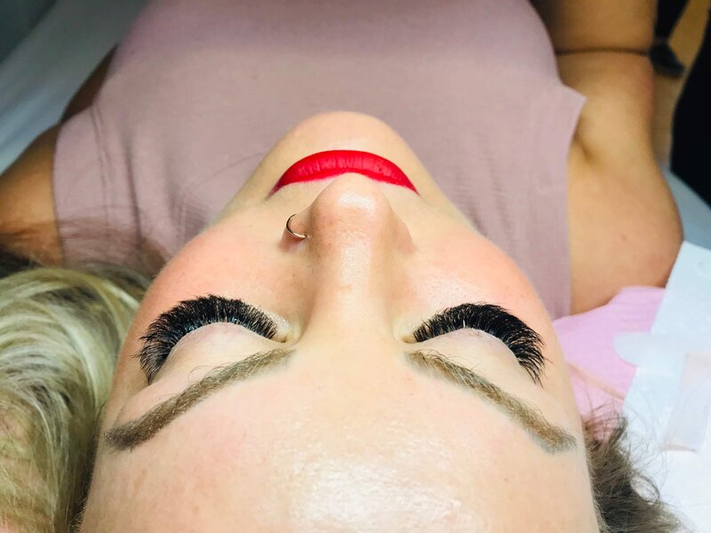A client laying down while showcasing her new lash extensions