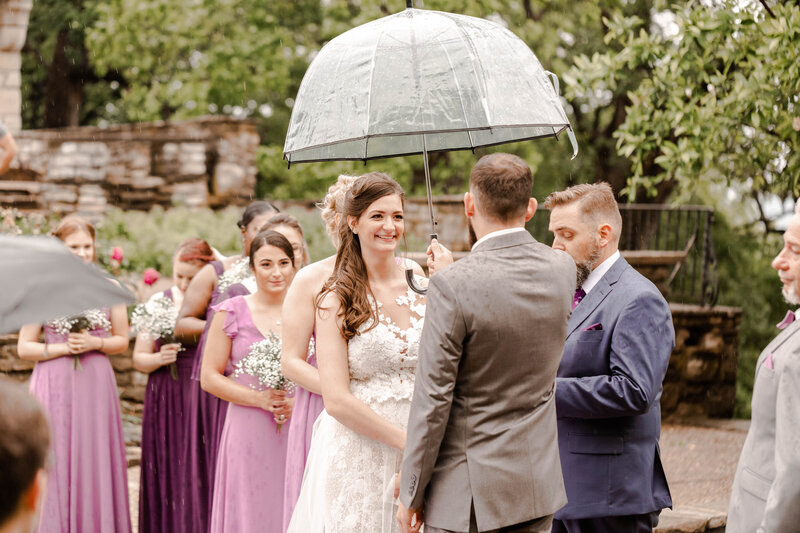 Romantic 'I Do' moment captured by Style & Grace Photography at Bee Tree Park, St. Louis, MO, with the couple exchanging vows under an umbrella, adding a personal and intimate touch to their wedding day