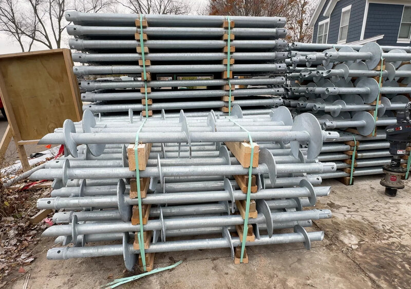 A large stack of helical piles at a warehouse yard. 