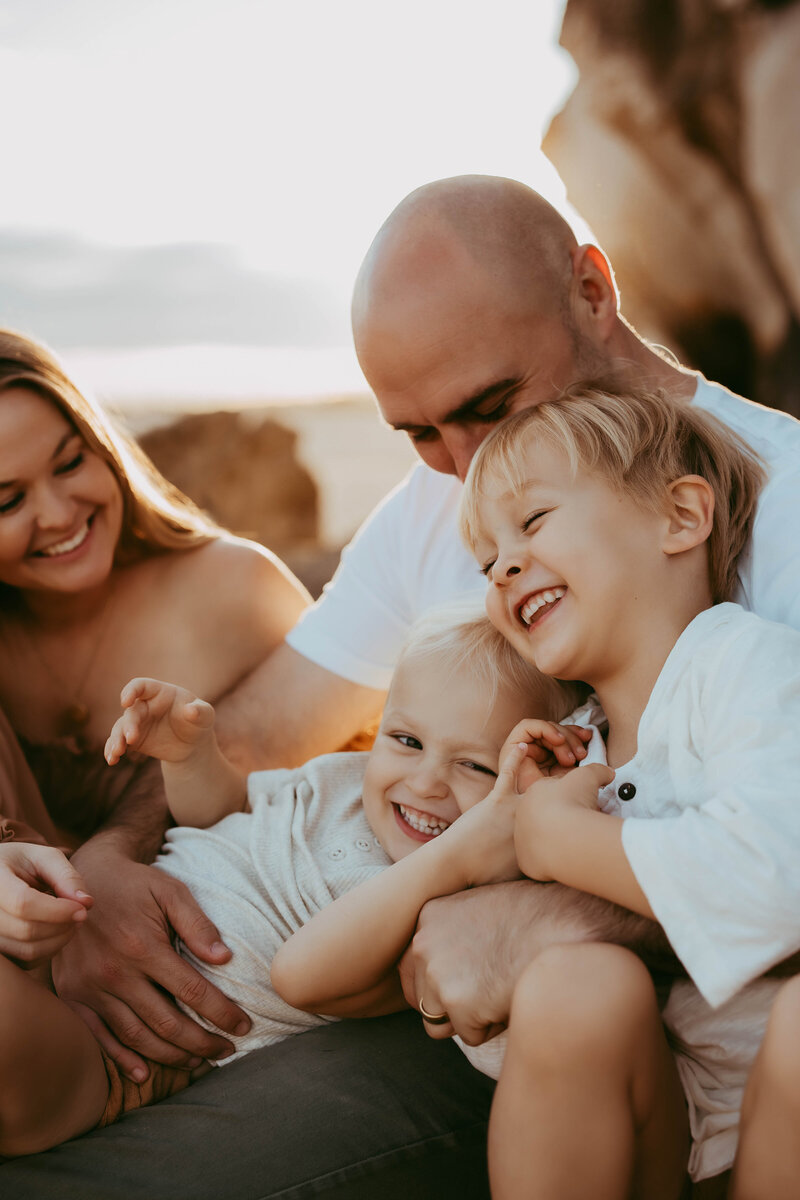 Parents cuddling children outdoors at golden hour, captured by Sydney family photographer Sophie Lea.