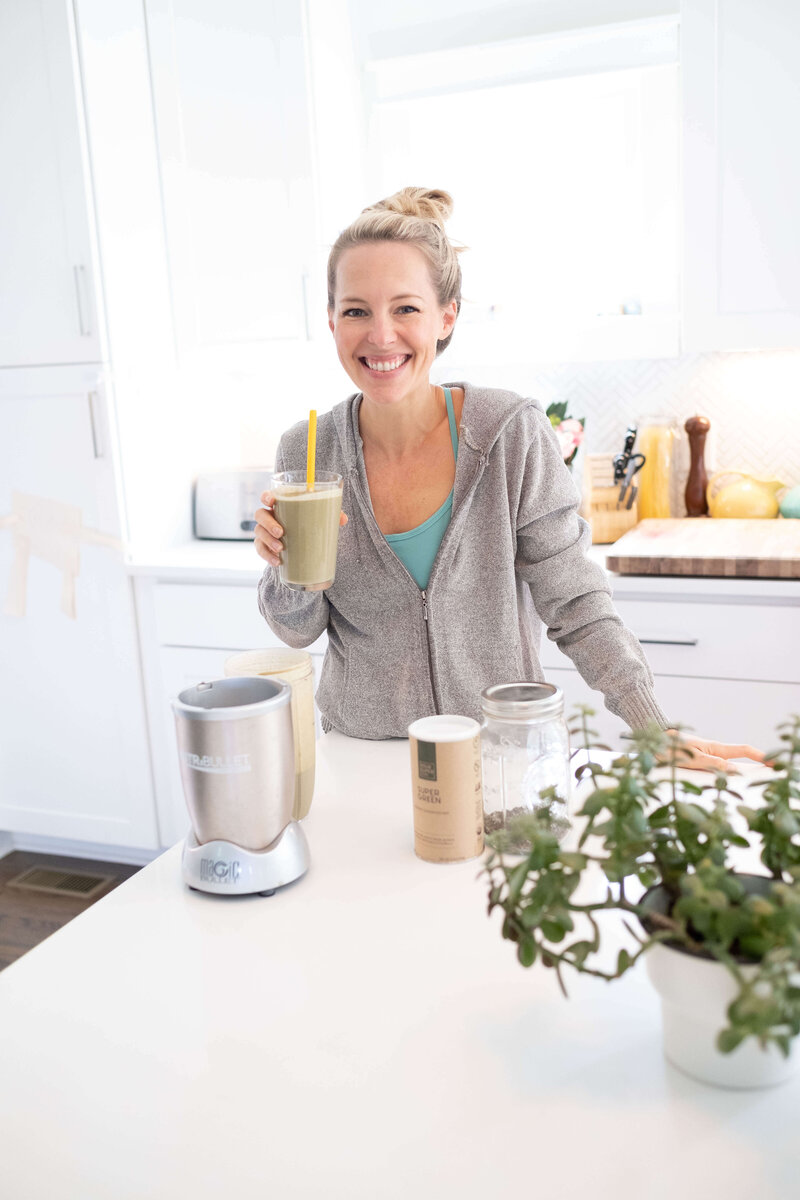 A healthy mom enjoying a green protein smoothie living a healthy lifestyle in the kitchen