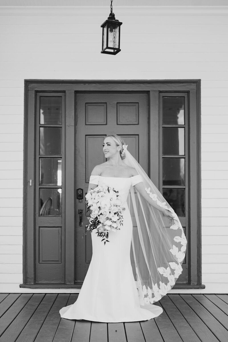 bride standing in dress and veil in front of door