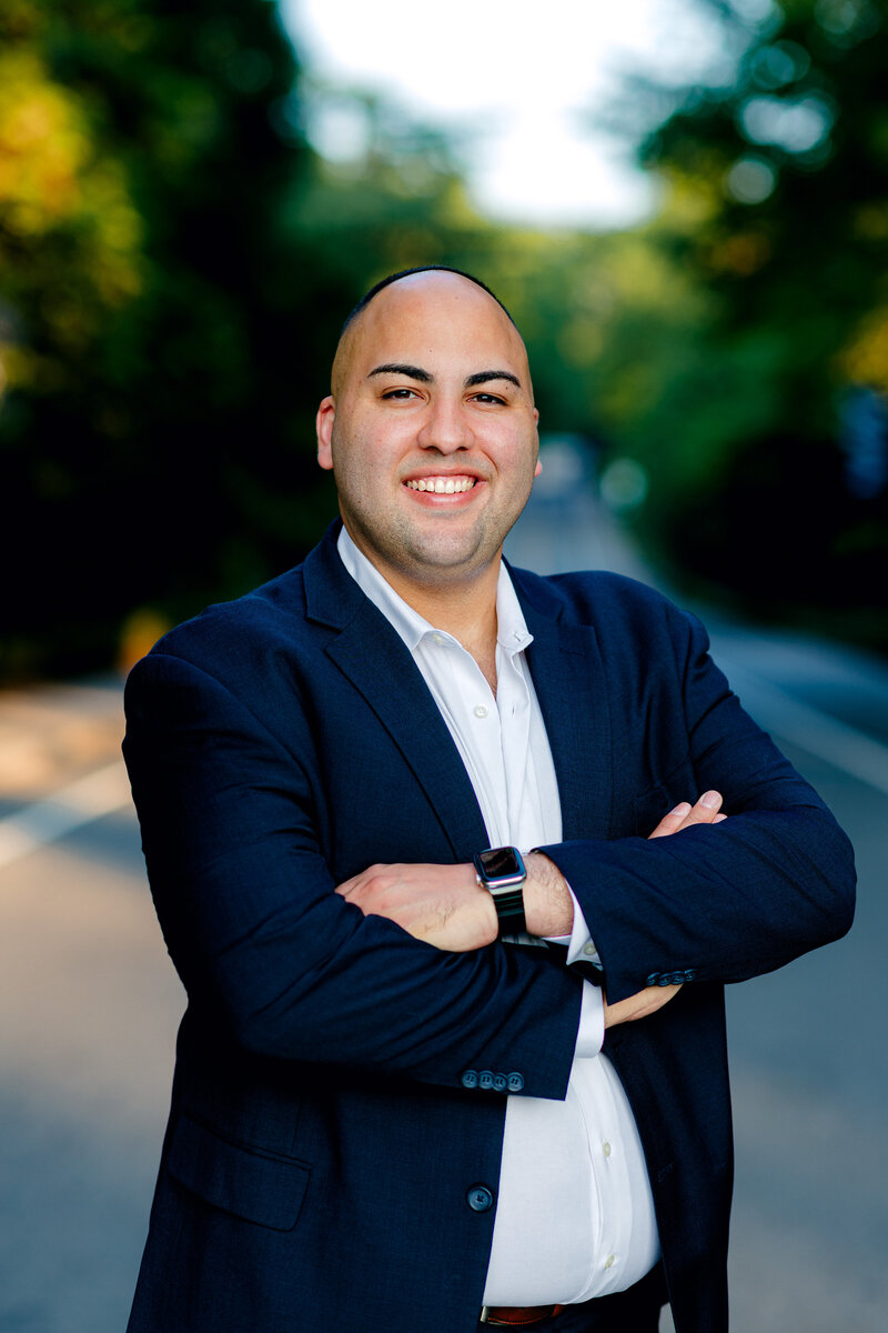 Man smiling in a suit crossing his arms for professional photos