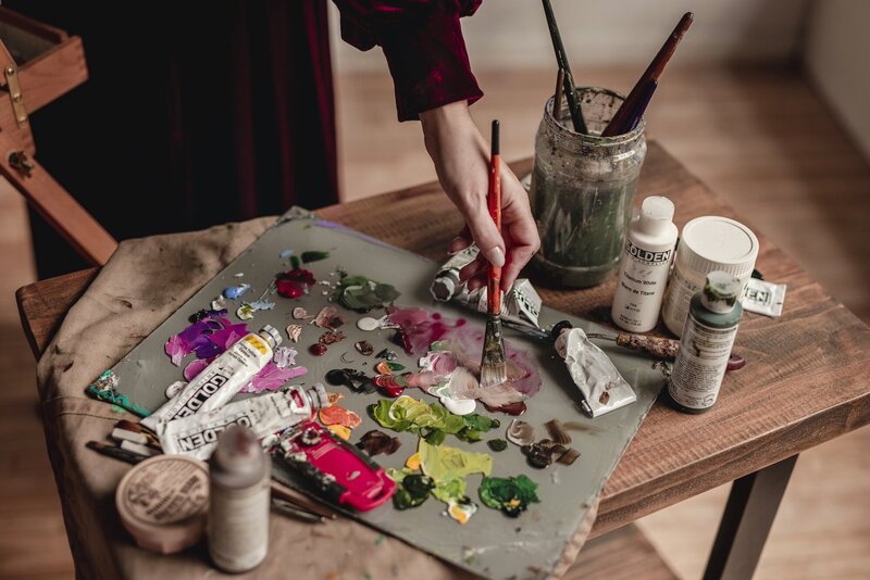 A flat lay of paints, paintbrushs, and a painting palette