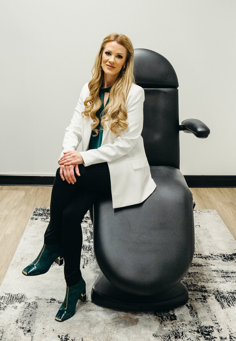 Nurse Injector Laura Maxwell sitting in lab coat on treatment chair in Salem, Oregon