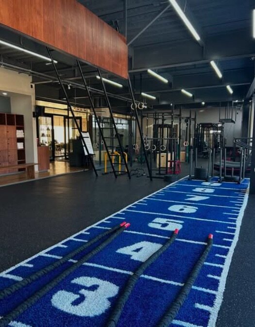 Interior of Athlex Studio in Polanco, Mexico City, showing modern gym equipment, turf track lanes, battle ropes, and suspension rigs in a sleek, well-lit functional training space.
