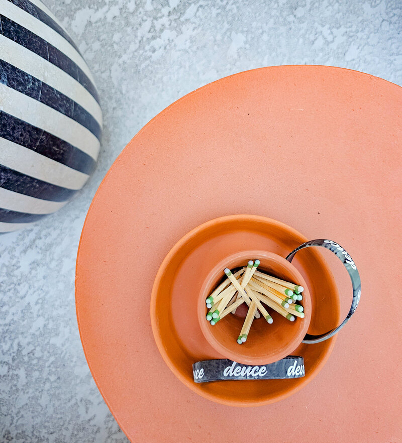 an above shot of a small clay planter filled with green tip matches and a rubber bracelet that says deuce. socialfizz