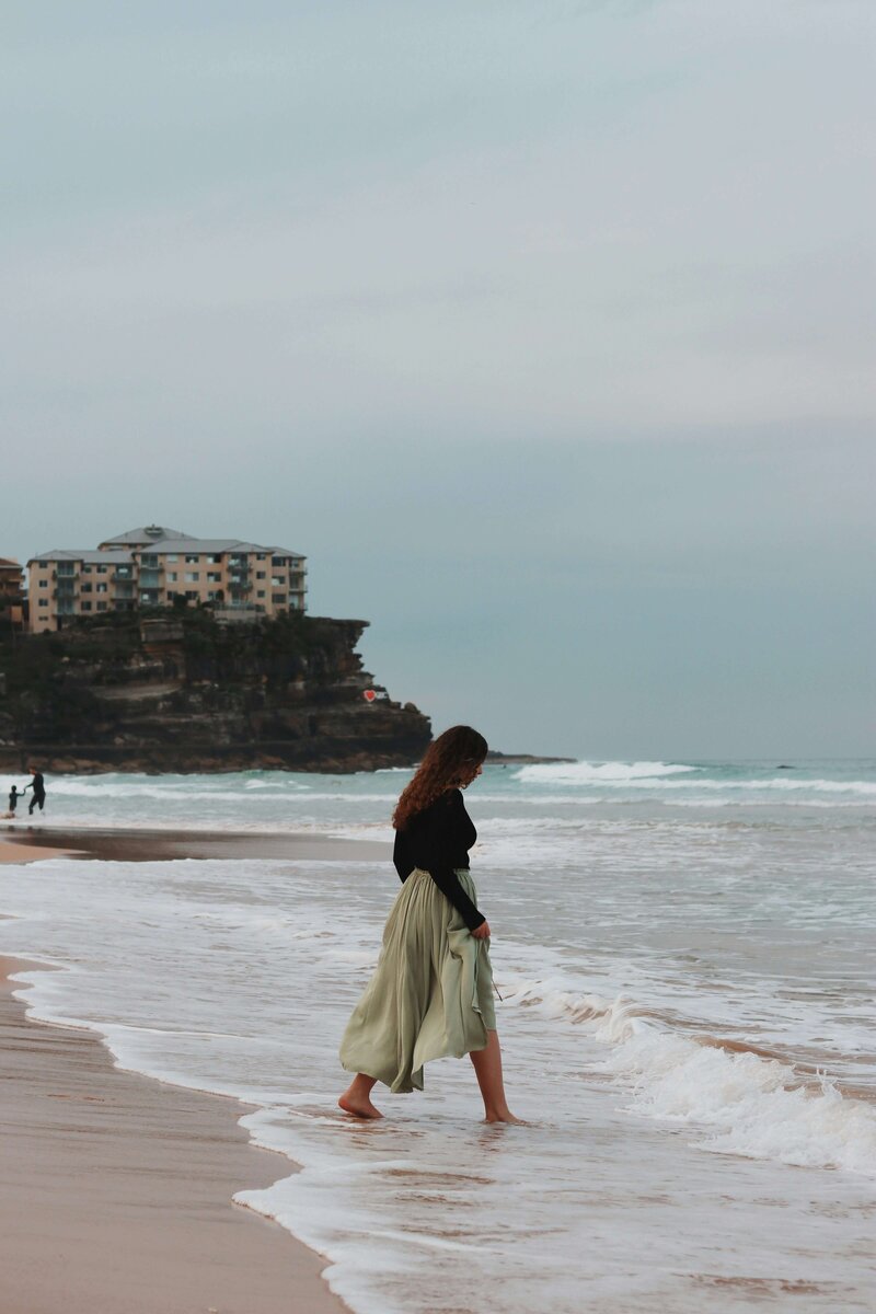 a woman taking a walk on the beach