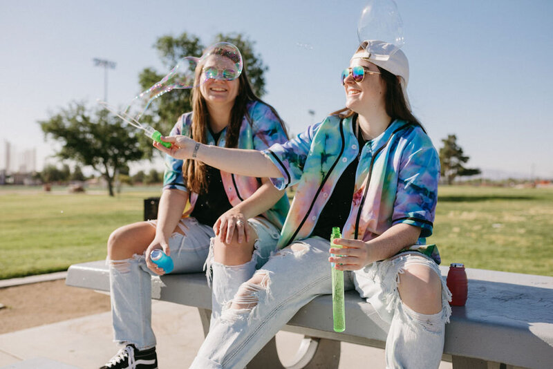 A girl makes bubbles while another girl laughs.